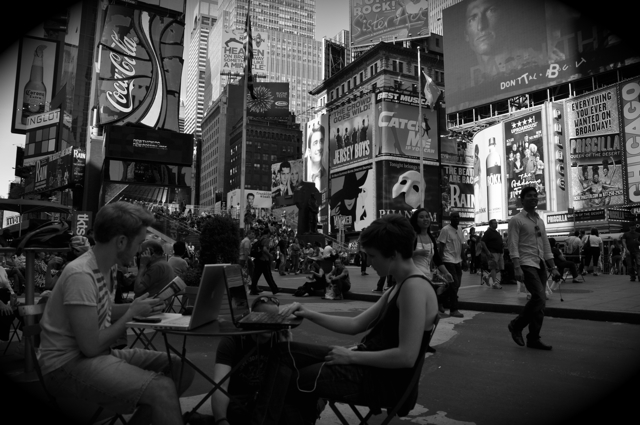 a man and woman sitting outside with their laptop