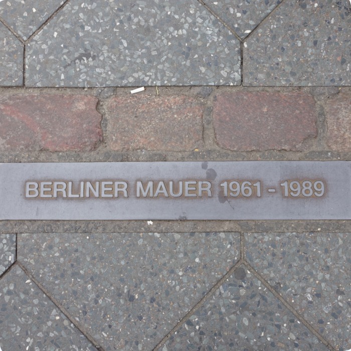 plaque near Checkpoint Charlie signifying where the Berlin wall stood.  If you can read the words right side up then you're standing on the East Side.  If you're reading it backwards then you are standing on the West Side.